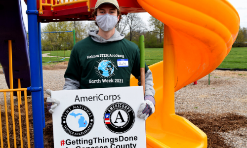 Man holding a sign that says Flint National Service Accelerator