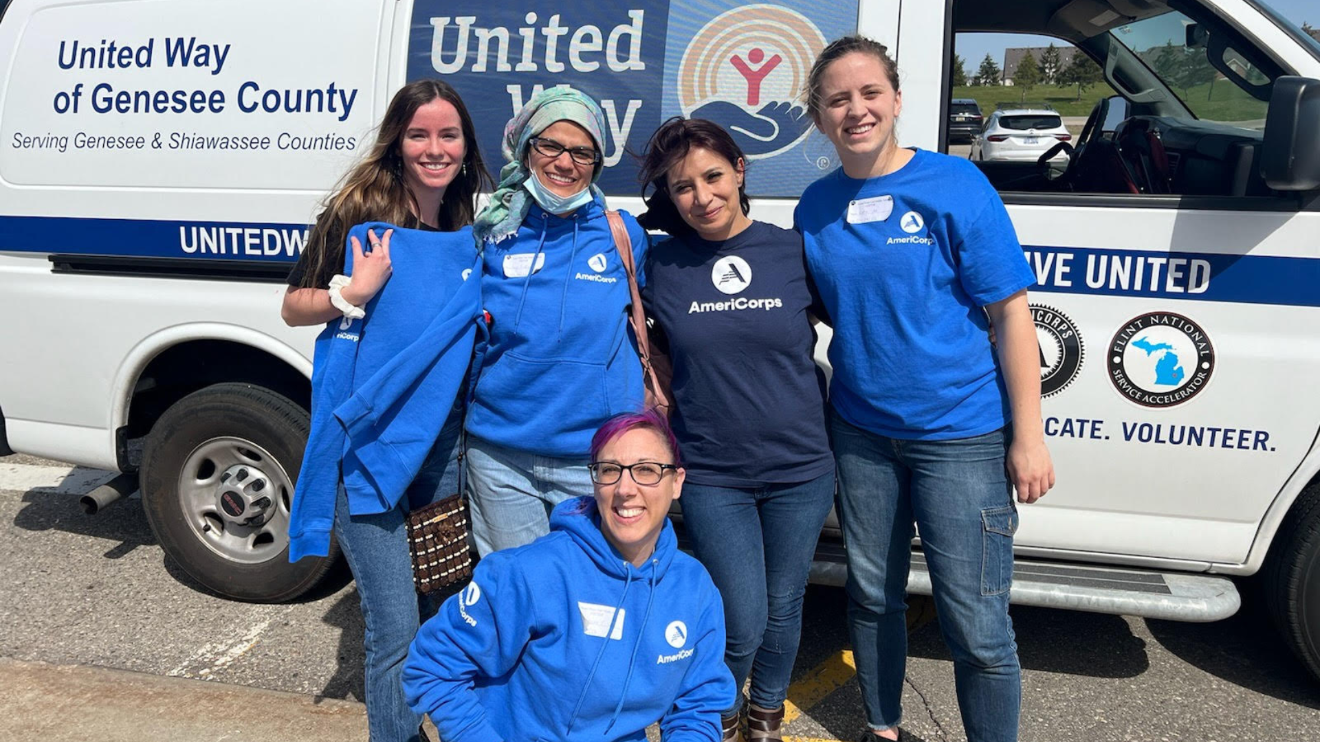 Five women in blue shirts in front of a united way van