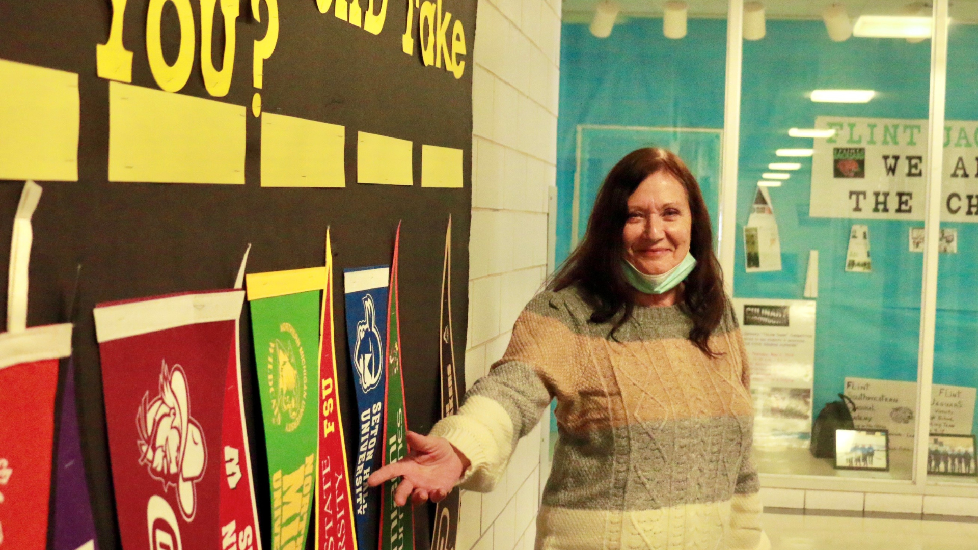 Woman in front of wall of college pennants