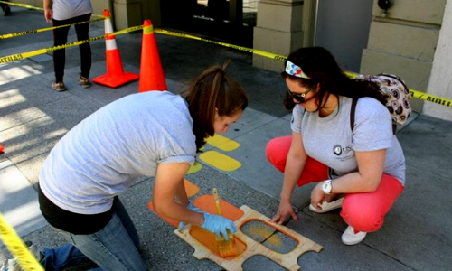 Two women squatting on the sidewalk